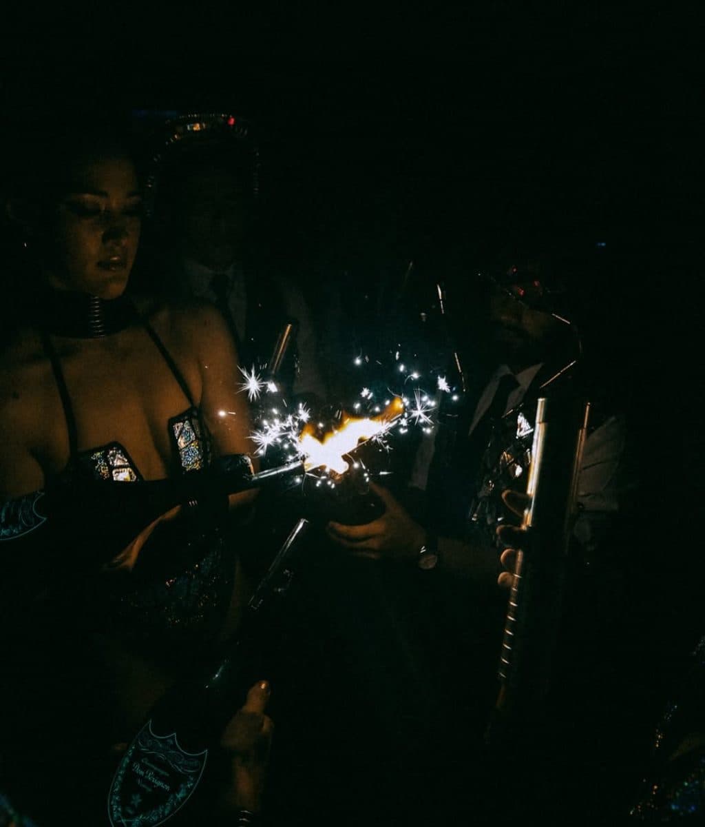 Woman holding a sparkler bottle in a dark club at Funky Buddha, before it closed