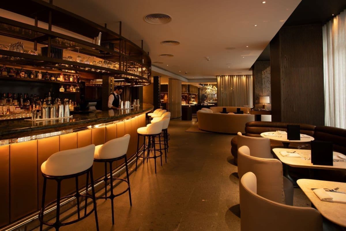 Long hotel bar with high stools and curved lounge seating