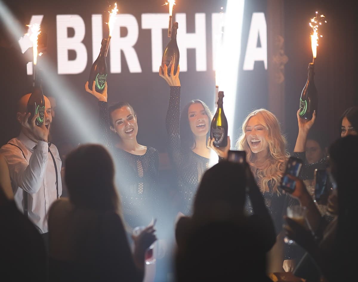Group of friends arriving at a London nightclub with a promoter greeting them at the entrance