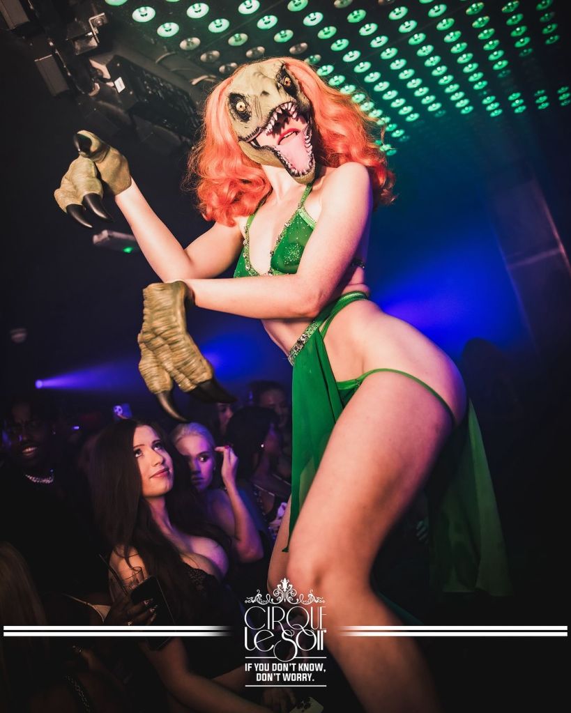 Cirque Le Soir performing on stage dressed as a dinosaur.