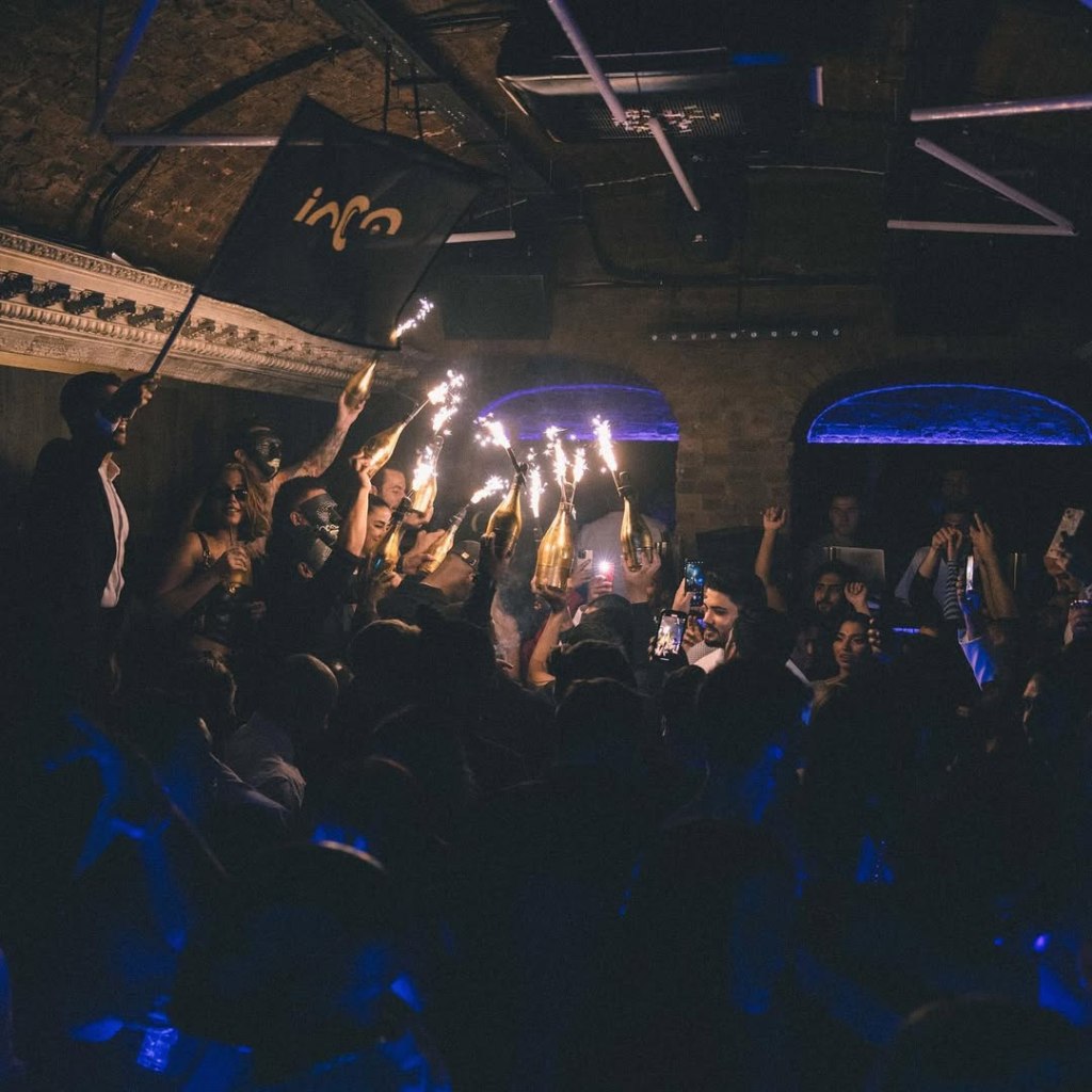 Luna London table clients enjoying a champagne show in the background while guests dance on the mainfloor.