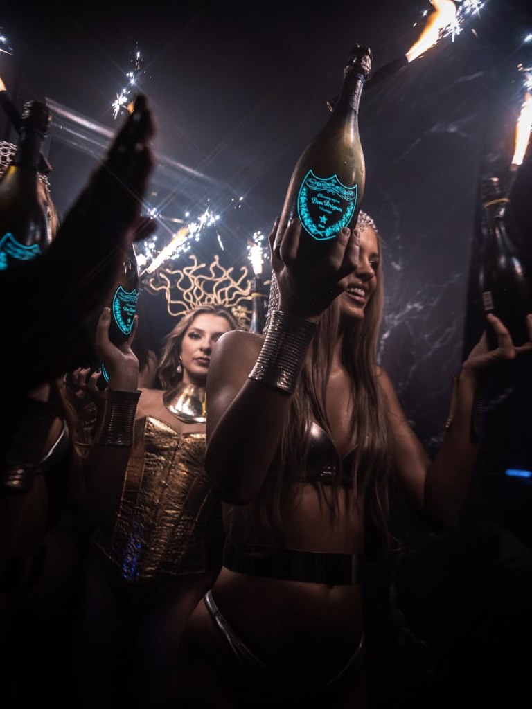 Bottle girls carrying champagne bottles to a Selene table.