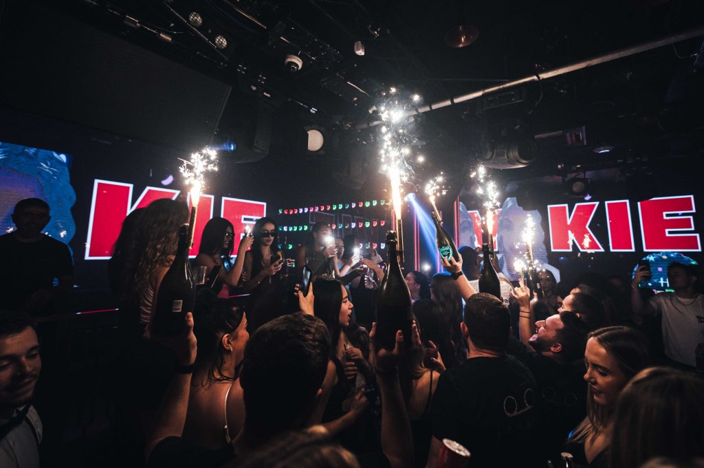 A group of girls on a VIP guestlist in London dancing at their table.