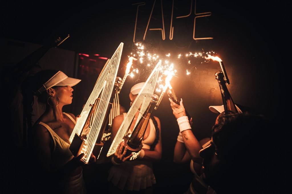 Bottle girls setting up a champagne show and lighting up sparklers at Tape London, an exclusive London nightclub.
