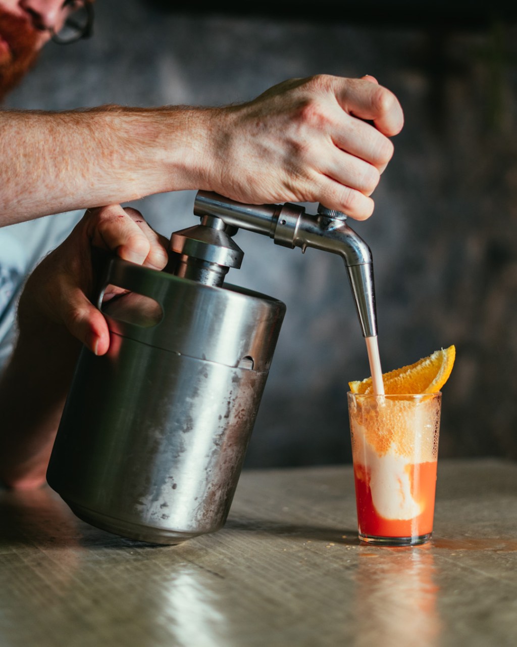 Bartender preparing a shooter topped with a tangerine slice at All My Gods Bar in London.