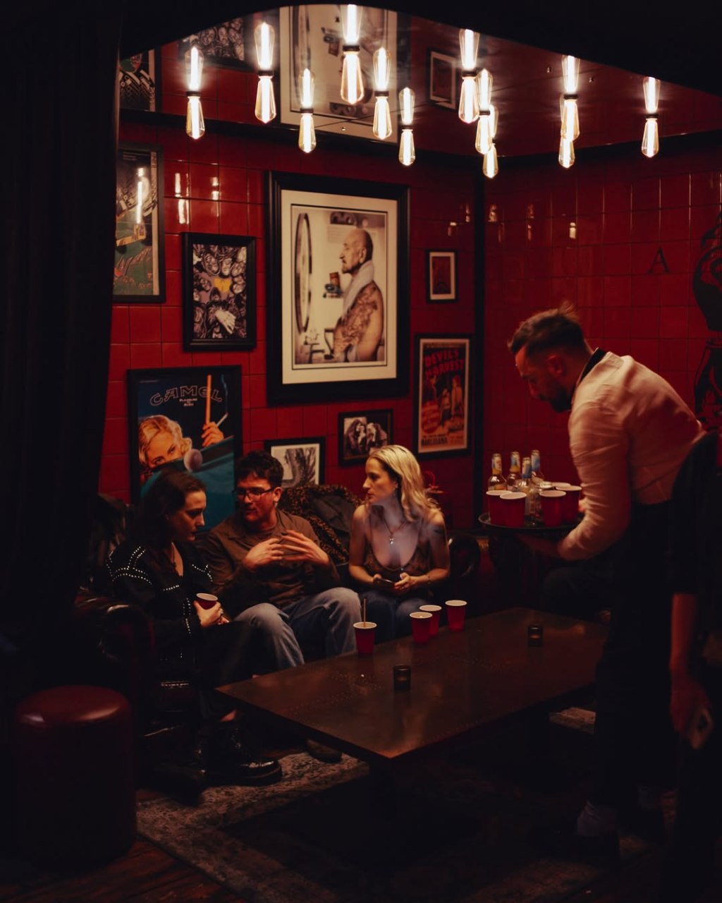 Waiter serving guests while they sit at a table inside As Above So Below bar in London