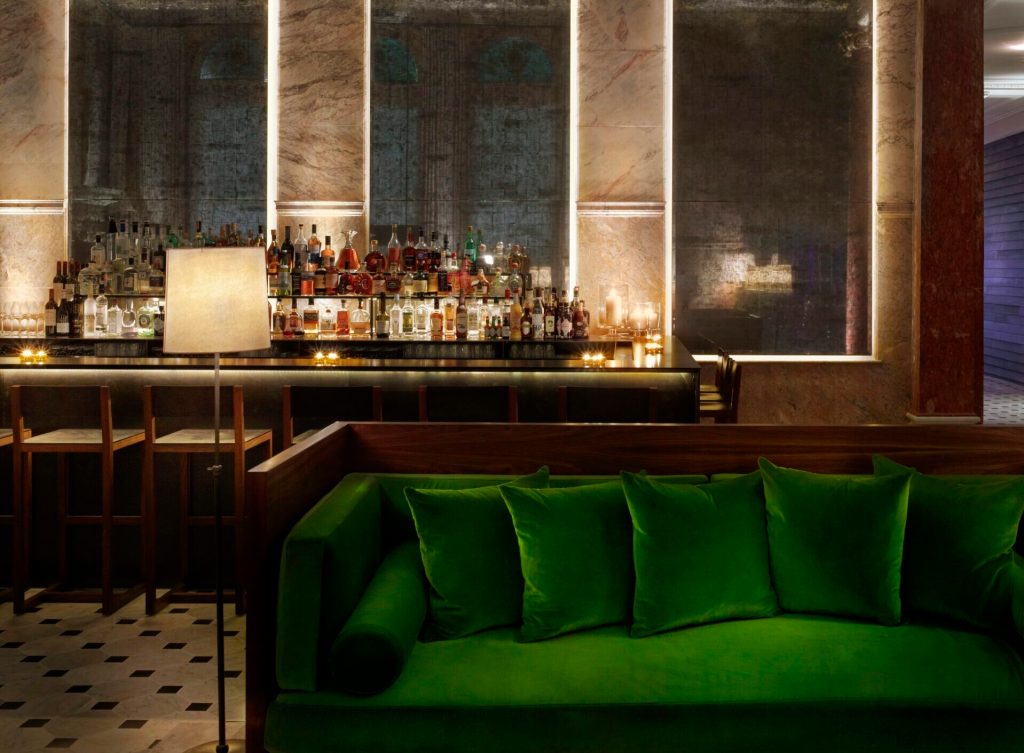 A green couch seating at the EDITION London Lobby bar.